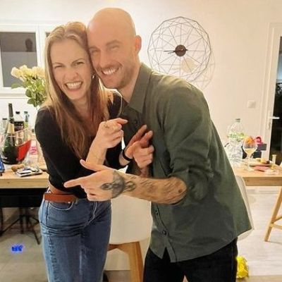 Both are holding each other while smiling at the camera.